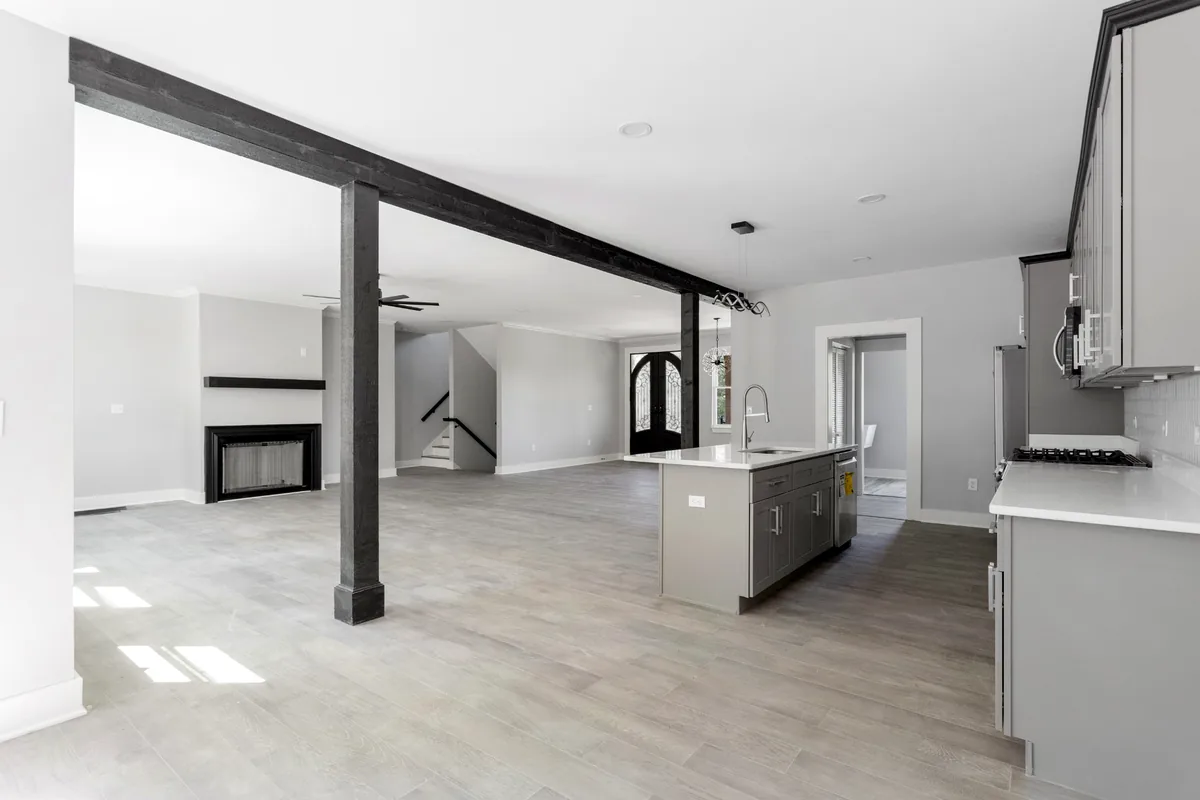 Open-plan residential interior with kitchen, living area and dark structural beams